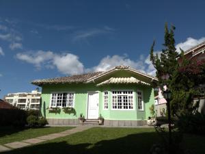 特雷索波利斯Casa Verde - Suíte 2 - Iúcas, Teresópolis, RJ的院子里的绿色房子,有白色门