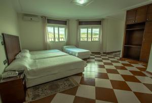 丹吉尔Motel Gzenaya的一间卧室设有两张床,铺有一个 ⁇ 板地板