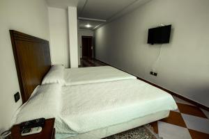 丹吉尔Motel Gzenaya的一间卧室设有两张床,墙上配有电视。