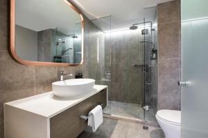 墨尔本墨尔本皇冠假日酒店的浴室配有盥洗盆和带镜子的淋浴