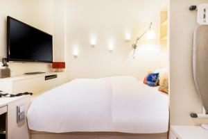 新加坡The Daulat by Hotel Calmo的白色的客房配有床和平面电视。
