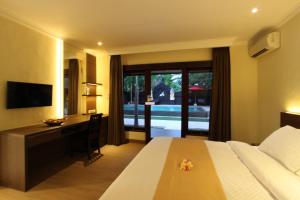 罗威那梅拉姆酒店的一间卧室配有一张床、一张书桌和一台电视