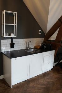 Hooge ZwaluweBoetiekhotel Ons Oude Raadhuis digitaal inchecken的厨房配有白色橱柜和水槽