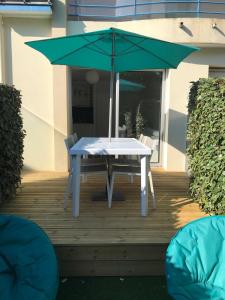波尔尼谢Studio Les Pétrels avec terrasse et jardinet à 2 pas de la plage的甲板上的一张带绿伞的桌子
