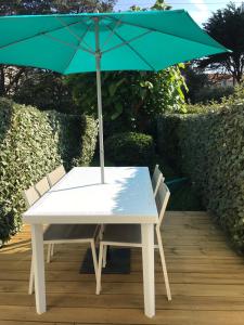 波尔尼谢Studio Les Pétrels avec terrasse et jardinet à 2 pas de la plage的顶部配有绿色遮阳伞的白色桌子