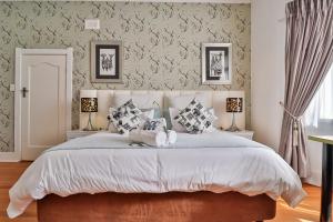 约翰内斯堡Sunbury Bed and Breakfast的一间卧室配有一张带两盏灯的大型白色床。