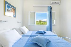 罗达Amorossa Beachfront Village by Konnect, Roda Corfu的一间卧室设有蓝色的床和窗户。