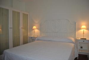 SuesaPosada de Suesa的卧室配有白色的床和两张台灯。