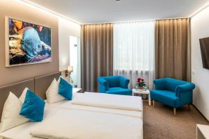 林茨洛可莫蒂夫酒店的酒店客房,配有一张床和两张蓝色椅子