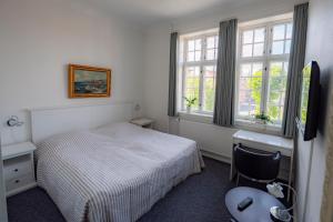 伦讷Det Gamle Posthus的一间卧室配有一张床、一张书桌和窗户。