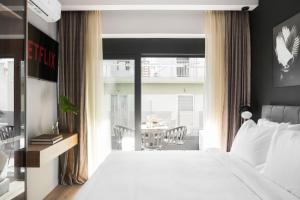 雅典LUX&EASY Athens Downtown Apartments的一间带白色床的卧室和一个阳台