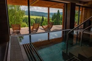 德尔内夫奥里克Amenity Hotel & Resort Orlické hory的享有带椅子的游泳池景致的度假屋