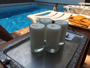 塔拉波托Posada del Angel Hotel的游泳池旁桌子上放着三杯牛奶的托盘