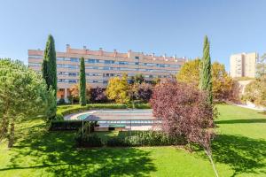 马德里Las Encinas Design Apartment in Conde Orgaz - Madrid的一座公园,有一座建筑的背景
