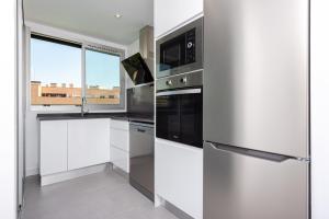马德里Las Encinas Design Apartment in Conde Orgaz - Madrid的厨房配有白色橱柜和不锈钢冰箱