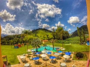 伊泰帕瓦Villa Itaipava Resort & Conventions的享有带桌子和遮阳伞的游泳池的景色