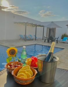 拉多拉达伊萨贝拉酒店的一张带水果和一瓶香槟的桌子以及一个游泳池