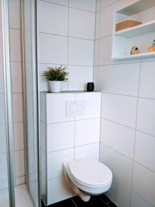 库克斯港Dat lütte Strandhuus的白色的浴室设有卫生间和植物