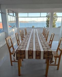 LlachonHospedaje y Restaurante Saywa的一张长桌,房间带椅子和窗户