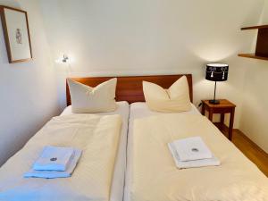 黑灵斯多夫Villa Schlossbauer - Ferienwohnung 13的配有2张床的客房内配有白色床单和毛巾