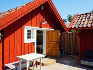 Mellösa5 person holiday home in Mell sa的红色谷仓,有门,甲板上设有长凳
