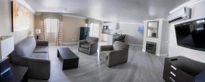 拉斯维加斯Alexis Park All Suite Resort的客厅配有沙发、椅子和电视