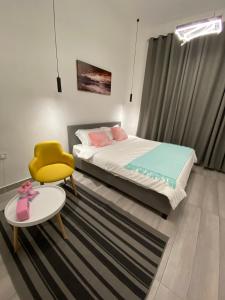 塞拉莱Platinum plus mirbat的一间卧室配有一张床、一张黄色椅子和一张桌子