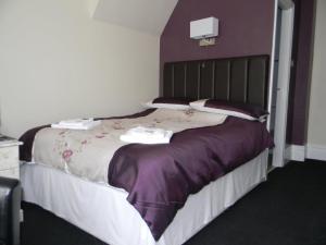 布莱克浦Devon Guest House的一间卧室配有一张大床,提供紫色床单和枕头
