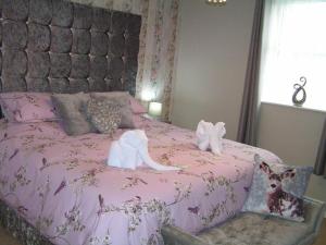 布莱克浦Devon Guest House的粉红色的床,上面有两只填充的动物
