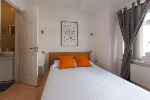 伦敦Tooting Rooms by DC London Rooms的卧室内的白色床和橙色枕头