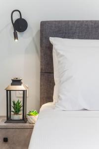 海若克利欧Raise Heraklion Boutique Apartments的一张带白色枕头的床和一张桌子上的台灯