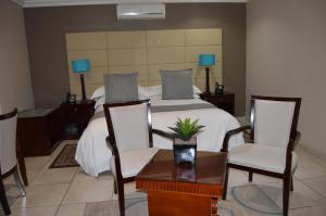 伯诺尼Lakeview Boutique Hotel & Conference Center的一间卧室配有一张带两把椅子和一张桌子的床。