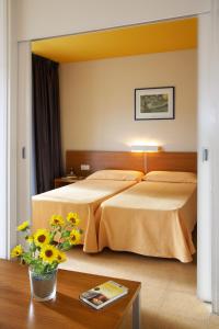 普拉加德阿罗科姆塔特圣霍尔迪公寓式酒店的配有床和鲜花桌的酒店客房