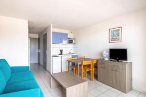 勒格罗-迪鲁瓦五月花公寓式酒店的一间带蓝色沙发的客厅和一间厨房