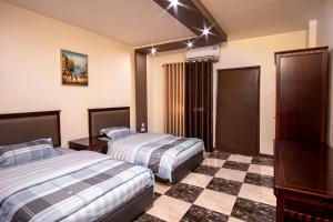 亚喀巴Al Riyati Hotel Apartments的酒店客房带两张床和一张 ⁇ 板