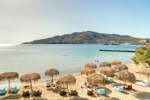波西多尼亚Boutique ''Di Mare'' Hotel & Suites的一个带草伞和椅子的海滩和水