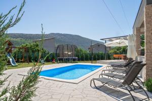 奥米什Villa Naklice的一个带两把椅子的游泳池和一个游乐场