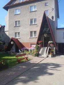 科尔别卢夫Apartamenty Bogusia Korbielów Pilsko的前面有长凳和鲜花的建筑