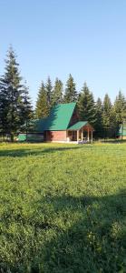 扎布利亚克Eco Village Podgora Household Kaljevic的田野上带绿色屋顶的红色谷仓