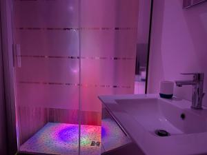 卡塔尼亚Cutapp Guest House的浴室配有水槽和带紫色灯的淋浴