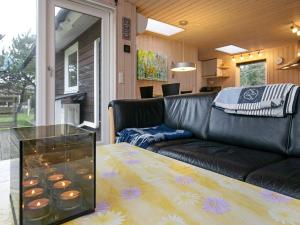 乌尔夫堡6 person holiday home in Ulfborg的客厅配有黑色真皮沙发和玻璃桌