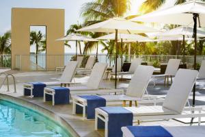 檀香山The Twin Fin Hotel的一个带白色躺椅和遮阳伞的游泳池
