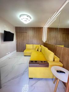 坎波斯杜若尔当Flat da Babi, MODERNO, LUXUOSO, EQUIPADO e 600mb wifi的客厅设有黄色沙发和电视