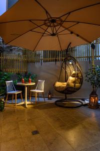 塞萨洛尼基BLACKHAUS Apartments的庭院配有遮阳伞、椅子和桌子。