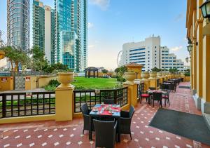 迪拜Ramada Hotel, Suites and Apartments by Wyndham Dubai JBR的餐厅位于带桌椅的带建筑的阳台