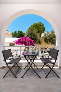 佩里萨Kasteli Luxury Rooms的阳台配有一张桌子和椅子,并种植了粉红色的鲜花