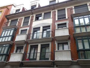 奥维多Apartamento de La Casona de Riomera的一座高高的砖砌建筑,设有窗户和阳台