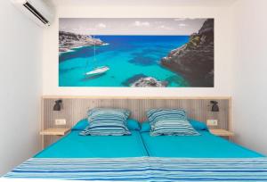 波连萨港埃洛酒店的卧室配有一张蓝色的床,墙上挂着一幅画