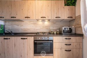 贡内萨Mary's House - WiFi & Private Parking的厨房配有木制橱柜、炉灶和微波炉。