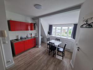 罗斯托克Nikolai Appartements的厨房配有红色橱柜和桌椅